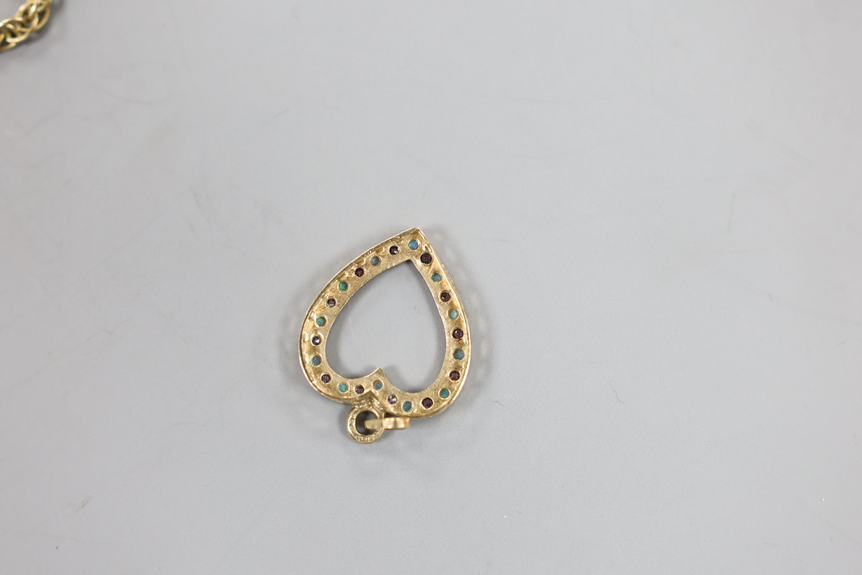 A modern 9ct gold, ruby and white opal set heart shaped open work pendant, 27mm and a 9ct gold chain, 38cm, gross weight 10.1 grams.